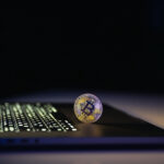 Bitcoin coin near laptop on black background. Finance and crypto money concept.