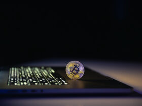 Bitcoin coin near laptop on black background. Finance and crypto money concept.